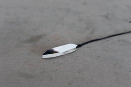A delicate leaf-shaped pendant made of silver or white metal, with a simple and elegant design that would complement a variety of outfits.