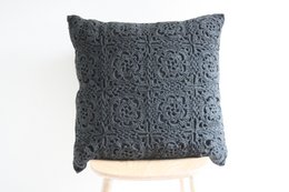 Large dark gray crochet cushion with intricate floral pattern.