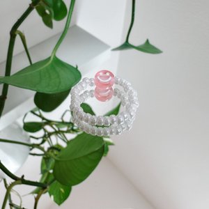 Parelring gemaakt van witte glaskralen met een roze smiley