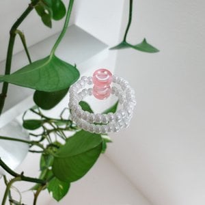 Parelring gemaakt van witte glaskralen met een roze smiley