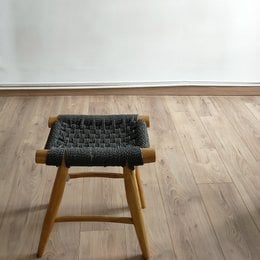 Teak stool with woven black seat, featuring a simple, minimalist design with natural wood legs.