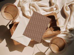Rectangular thank you card with textured pattern, accompanied by wooden decorative elements on a soft fabric background.
