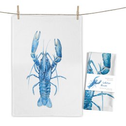 A blue lobster illustration on a white tea towel. The towel features a detailed, watercolor-style depiction of a lobster in shades of blue.