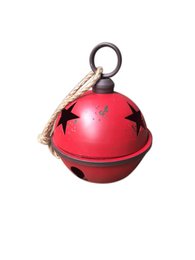 Red and green metal Christmas bells with star cutouts, hanging on a Christmas tree.