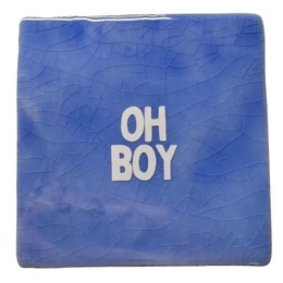 A green tile with the text "LET THEM SMELL A POOPIE" in bold pink letters. The tile appears to be a decorative or humorous home accessory.