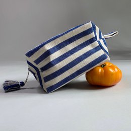 Handmade cosmetic bag in blue and white striped pattern, with a tassel zipper pull.
