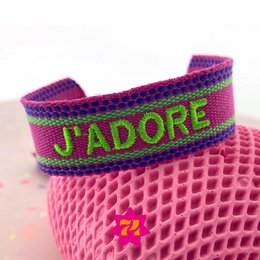  Woven bracelet in cyclamen and neon green colors with "J'adore" text. Made of woven material with a textured pattern.