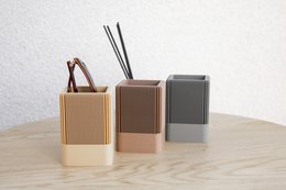 A modern, minimalist desk organizer set in earthy tones of light brown, dark brown, and graphite. The organizers feature a square shape and ribbed texture, providing a stylish and functional storage solution for your office or home.