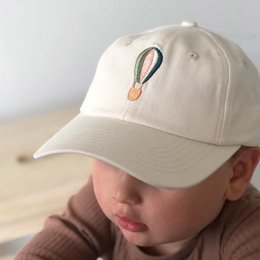  Beige baseball cap with a small hot air balloon embroidered on the front. The cap appears to be designed for children, with size variants for ages 1-4 years and 5-7 years.