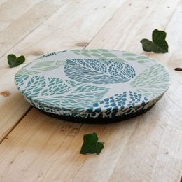 Round, flat food wrap in sizes XS to XL with a floral pattern design. Made of durable, reusable material for storing and covering food.