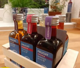Wooden crate containing various vinegar bottles in different flavors, including raspberry, apple, and balsamic varieties.