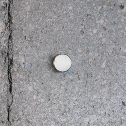 Round white wall magnet for holding toothbrushes.