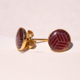 Stud earrings with round burgundy-colored stones in a geometric pattern, made of gold-toned metal.
