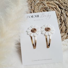 Daisy-shaped rose gold hair clips for kids, featuring a delicate floral design and a click-clack closure for secure wear.