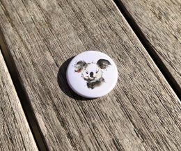 Watercolor fridge magnet with a cute koala motif. Circular magnetic button with a black and white design.