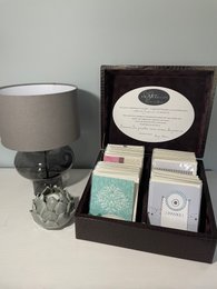 A box of 100 greeting cards in a decorative box with a lamp and other accessories.