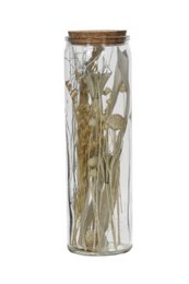 A clear glass jar containing dried flowers and stems, with a wooden lid. The jar has a cylindrical shape and the contents appear to be arranged in a decorative manner.