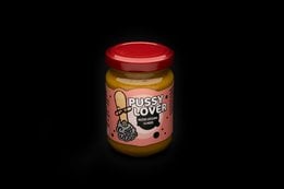 A glass jar containing a yellow mustard-based condiment with the label "Pussy Lover - honey mustard".