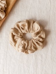 Beige modal ribbed scrunchie with a soft, textured appearance and a circular, gathered design.