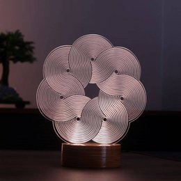 A modern, wooden table lamp with a unique, abstract flower-like LED light design. The lamp features a warm, natural wood base and a mesmerizing, illuminated pattern that creates a cozy, ambient glow.