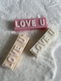 A set of decorative wooden blocks spelling out "LOVE U" in various pastel colors, including cream, beige, brown, dark brown, taupe, pastel green, aquamarine, baby blue, pink, lilac, yellow, and orange.