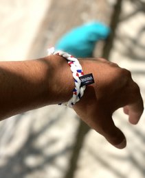 10 eco-friendly wristbands in a braided design with red, white, and blue accents. The wristbands are made of sustainable materials and feature a charm or pendant.