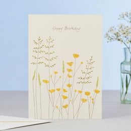 A birthday card featuring a colorful illustration of buttercup flowers against a light background. The card has the text "Happy Birthday" written on it.
