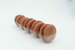 Delicate chocolate macarons in a row, featuring a smooth, round shape and a rich, cocoa-colored exterior. These bite-sized treats would make a delightful addition to any chocolate gift set.