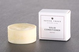 Solid conditioner in a round, pale yellow shape with a white box packaging. Intensive care for hair.