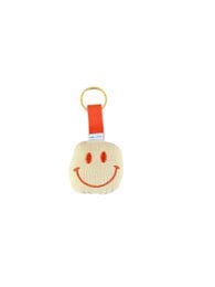 Smiley face keychain, yellow cream fabric, orange red ribbon, happy smiling expression, round shape.