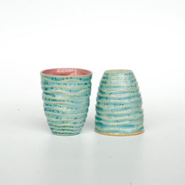 Stoneware fluid cup in coral bay color with a textured, striped pattern.