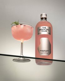  A 99cl bottle of Mocktail Rhubarb Rush, a non-alcoholic beverage with a pink, rhubarb-based color and garnished with a sprig of rosemary.