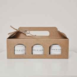 A set of 3 floral-scented candles in a gift box. The candles are white and the box is made of brown kraft paper.