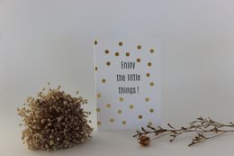 Greeting card with text "Enjoy the little things!" and gold polka dot pattern. The card is accompanied by a small dried flower arrangement.