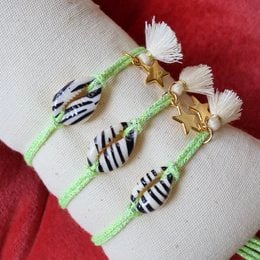 Green and white beaded anklets with striped and star charms.