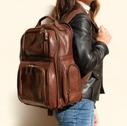 Tan leather backpack with multiple zippered compartments and a striped fabric panel on the front.
