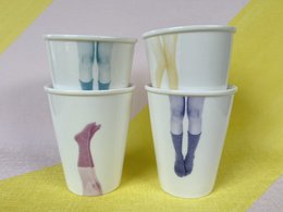 Set of 4 white ceramic mugs with colorful leg designs. The mugs feature a variety of leg shapes and styles, including long and short legs, in various shades of blue and purple. These unique and playful mugs would be a fun addition to any kitchen or dining set.