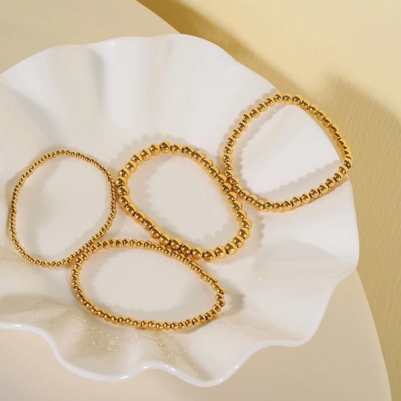 Aquilea - Pile de bracelets en perles d'or