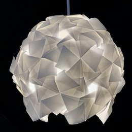 A modern, geometric pendant light with a white, faceted shade that creates a striking, sculptural appearance.