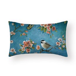 Cushion cover with a Great Tit bird perched on a branch with pink and white flowers against a teal blue background.