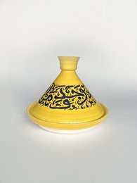 Yellow ceramic pot with intricate black floral pattern. Suitable for cooking and serving various dishes.