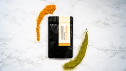 Matcha green tea powder in a black and orange package. The powder has a vibrant green color and a smooth, fine texture, indicating high quality.