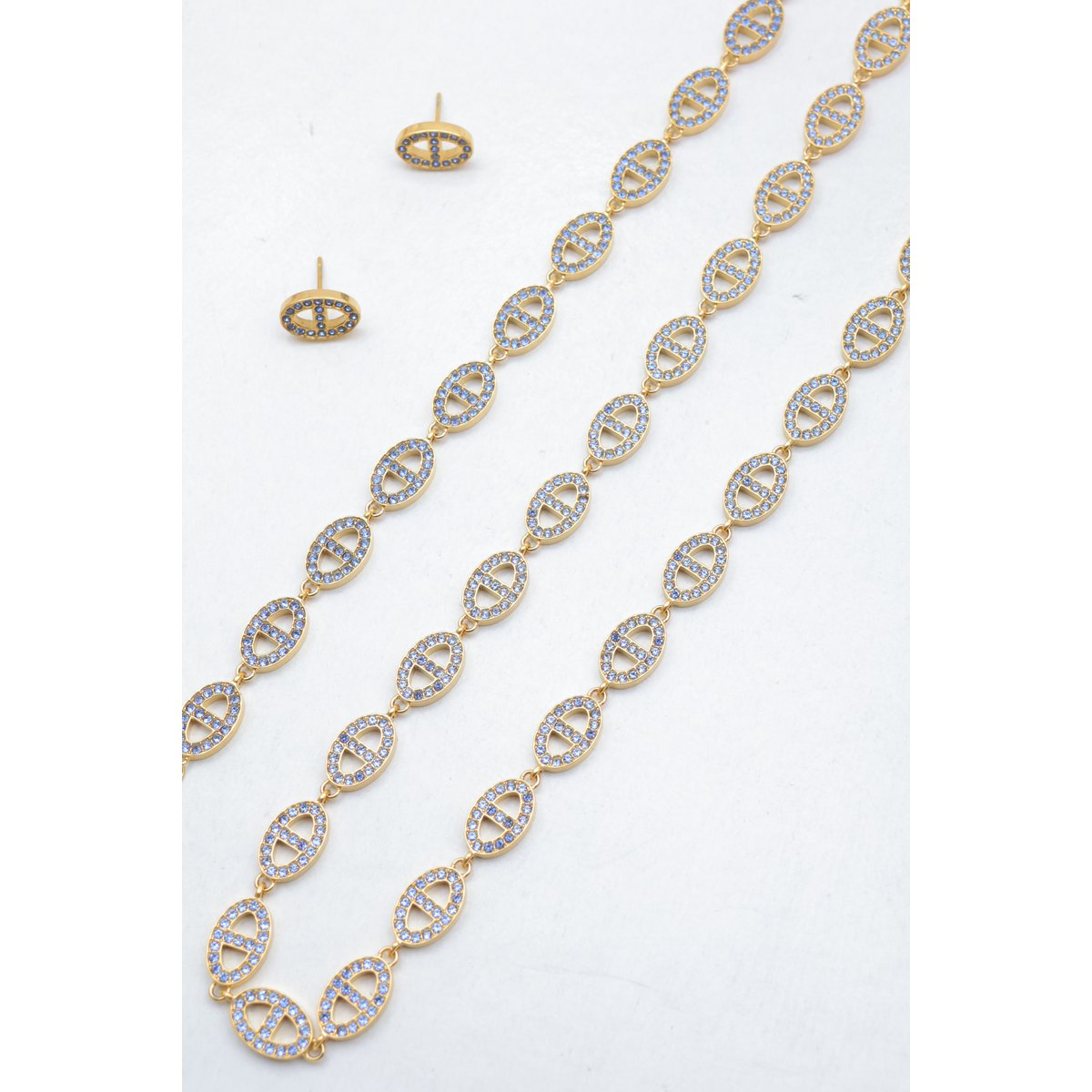 Ensemble assorti comprenant un collier, un bracelet en chaîne et une paire de boucles d'oreilles puces. Chaque bijou est composé d'une succession de maillons en forme de maille marine entièrement pavés de petits strass scintillants.
