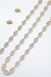 Ensemble assorti comprenant un collier, un bracelet en chaîne et une paire de boucles d'oreilles puces. Chaque bijou est composé d'une succession de maillons en forme de maille marine entièrement pavés de petits strass scintillants.