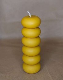 Stacked round candles in green, pink, and yellow colors. Made of raw beeswax material. Cylindrical shape with a simple, minimalist design.