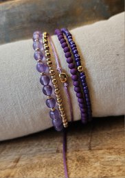 A set of purple beaded bracelets with a mix of different bead styles and textures, including round amethyst beads, faceted beads, and gold-toned accents.