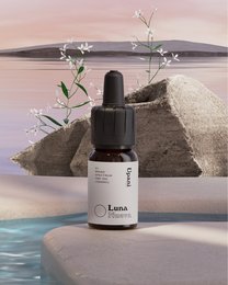 A small glass bottle of CBD oil with a dropper, set on a rocky outcrop overlooking a serene lake or ocean. The bottle is labeled "Luna" and contains 5% CBD.