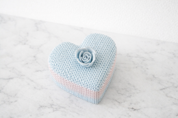  Decorative heart-shaped knitted-style storage box in pastel blue and pink colors.