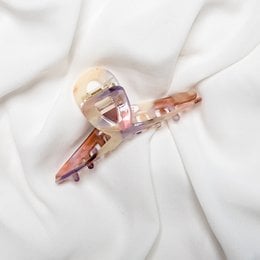 A pink plastic hair claw clip with a twisted design. The clip is made of a translucent pink material and has a simple, minimalist style.