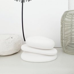 Three stacked white decorative stones with a black metal stand. Minimalist, modern home decor.